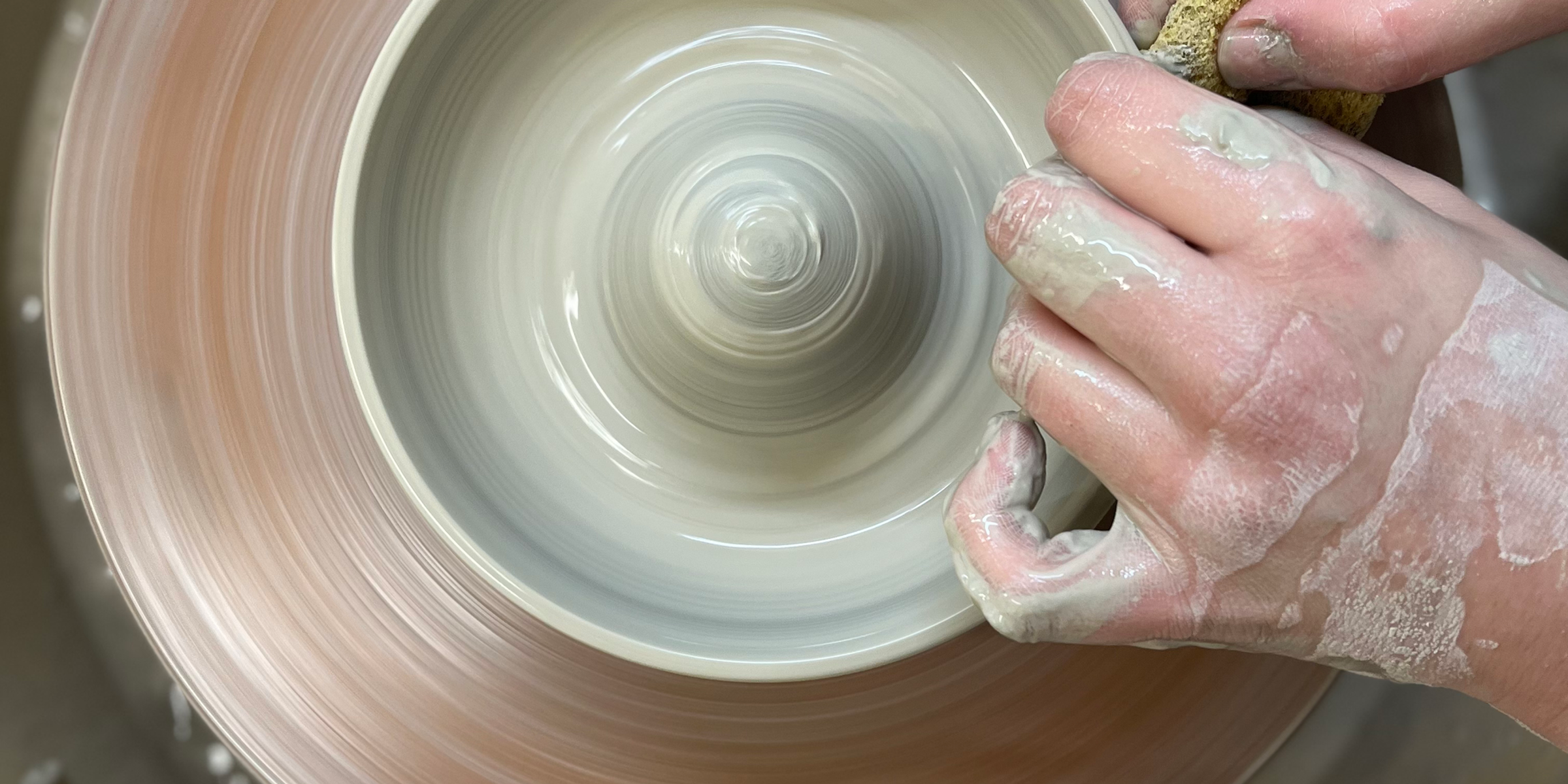 Dellaney's hands shaping a bowl on the pottery wheel